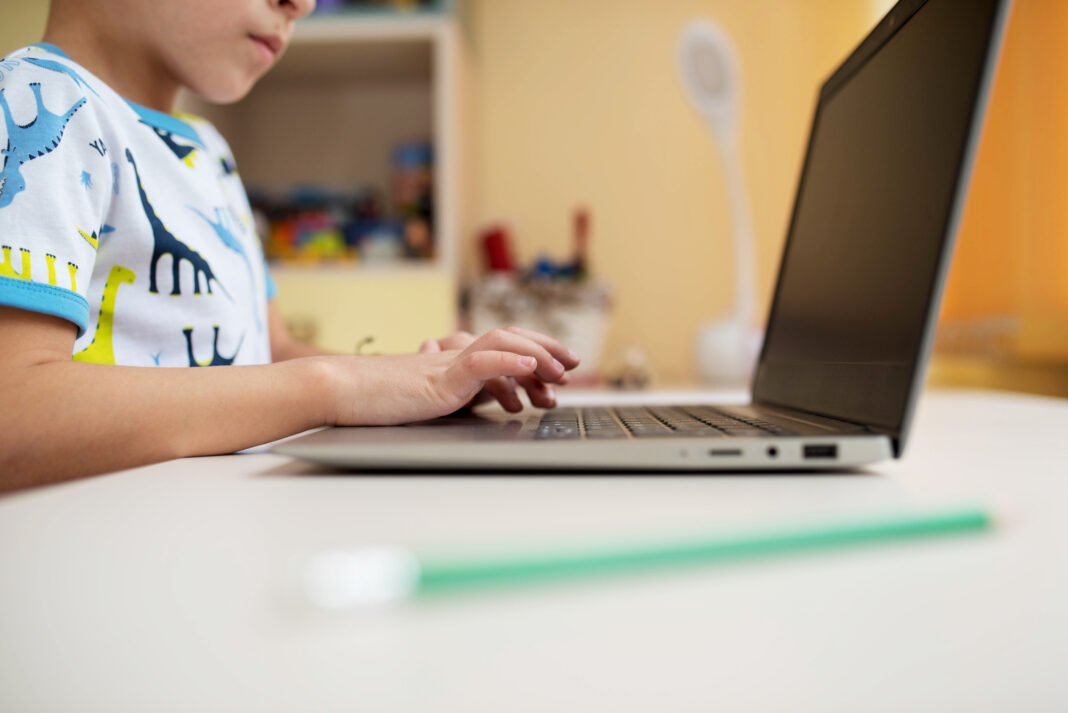 hands of a little boy on a laptop keyboard